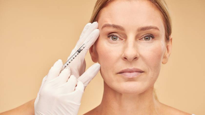 Mature woman receiving dermal filler injection near eyes – catalog image, not a real patient